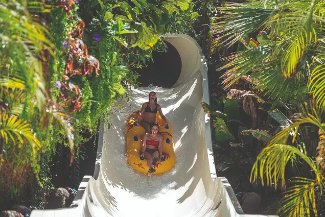Guests on the Jungle Raft water slide drifting through tropical scenery at Siam Park in Tenerife.