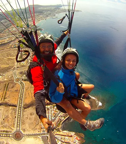 A tandem paraglider gliding above the coast of Tenerife.